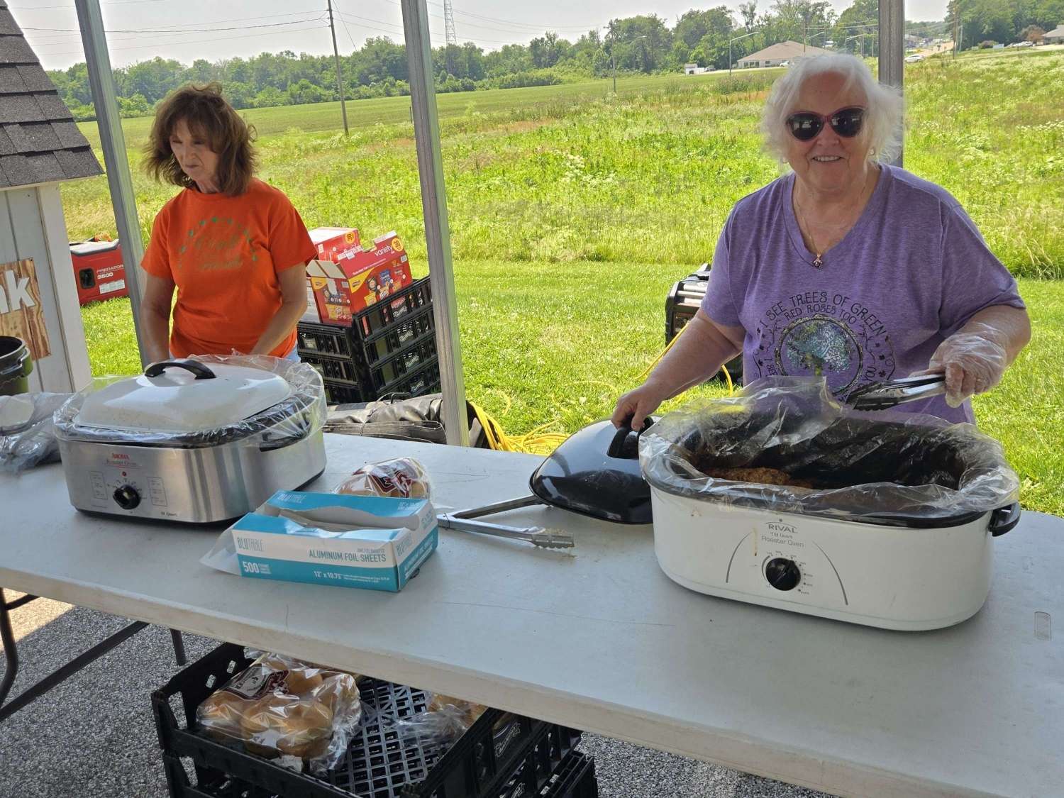 two women ready to serve grilled meat from roaster ovens