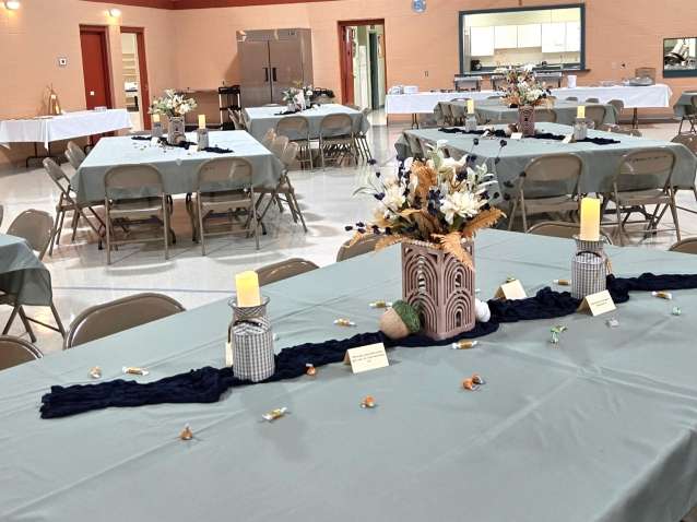 green tablecloths with beautiful centerpieces of metalic flower vases, electric candles, and individually wrapped candies